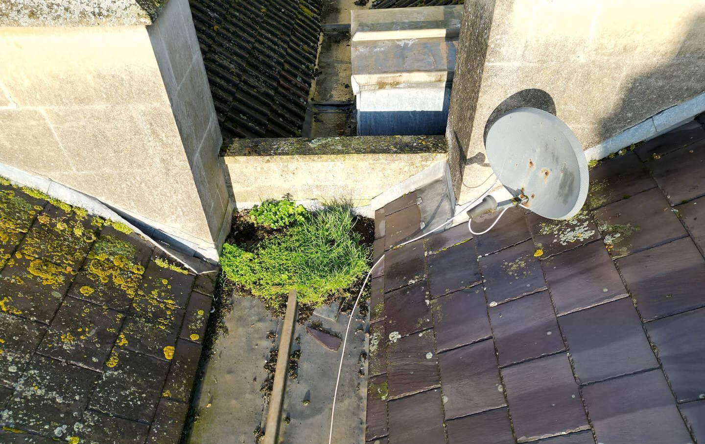 A satellite dish mounted on a sloped roof, equipped with a satellite dish