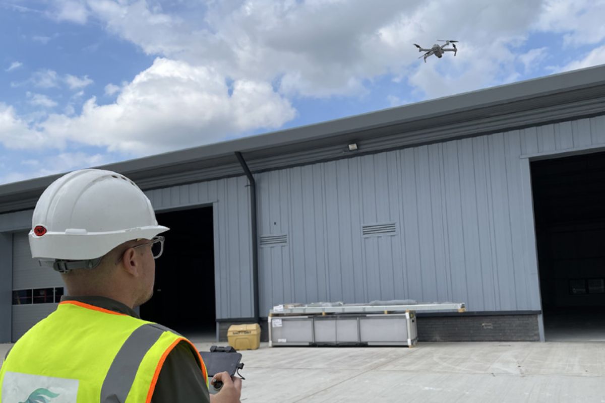 A man with a hard hat using a drone 